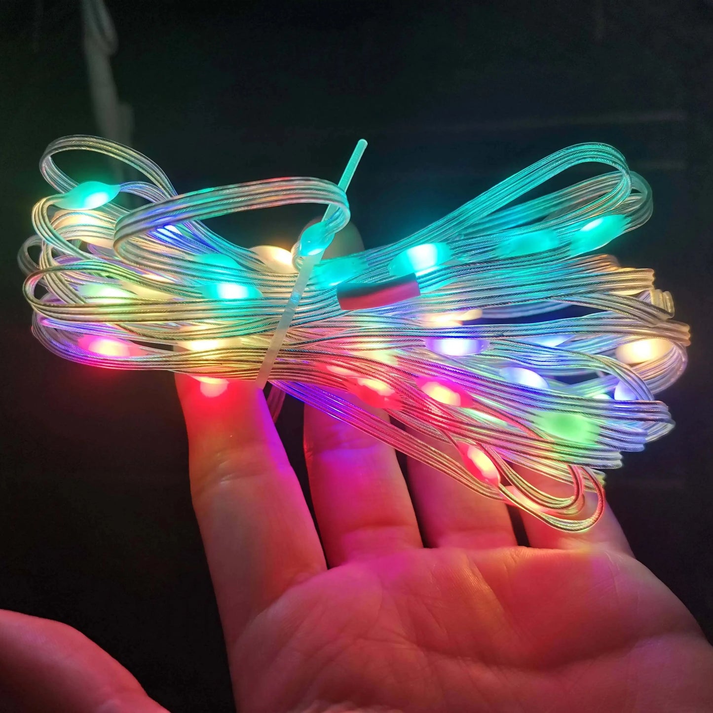 Hand holding RGBIC LED fairy string lights showing vibrant multicolor illumination along the transparent wire