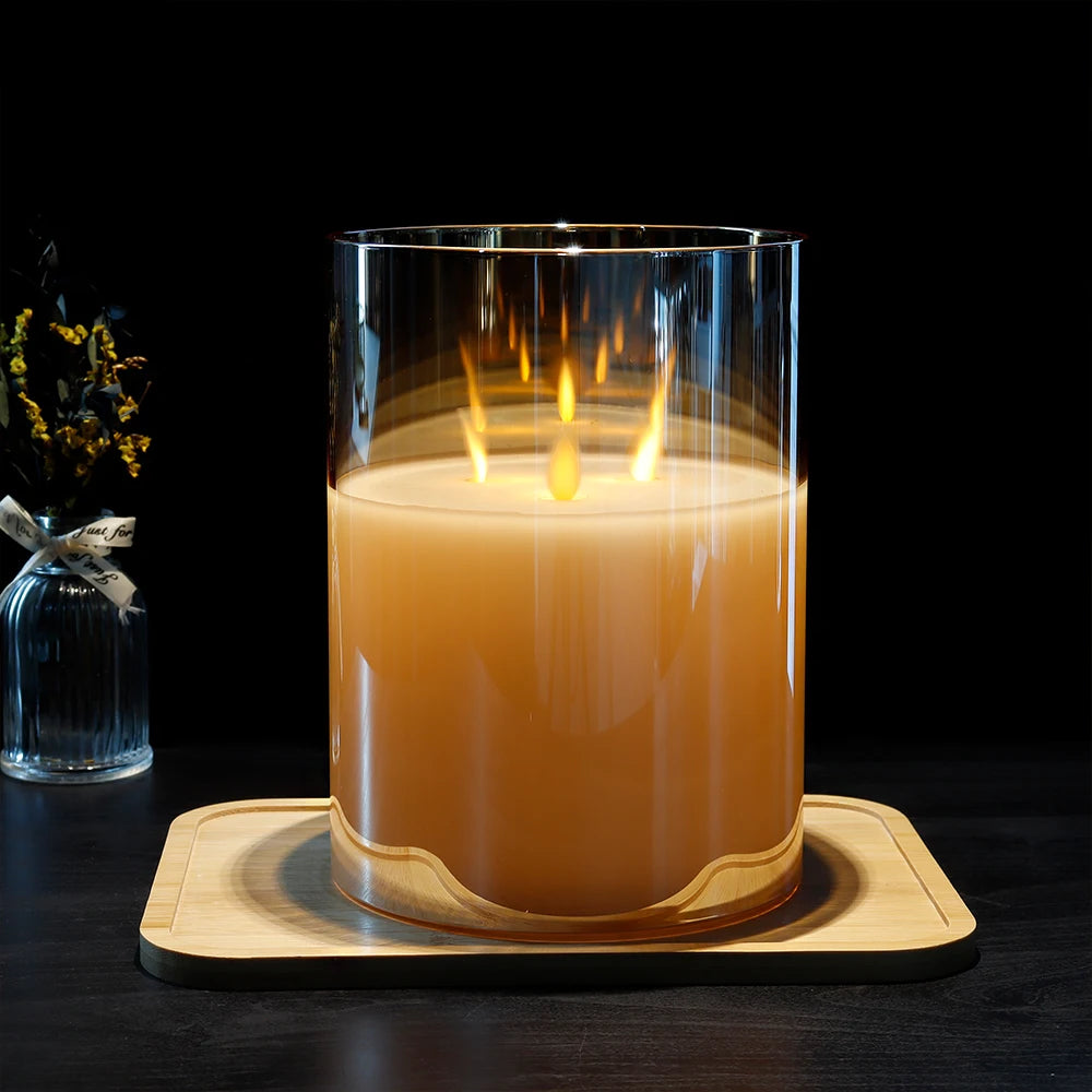 Large flameless paraffin wax candle with realistic dancing LED flames in clear glass holder on wooden tray, black background