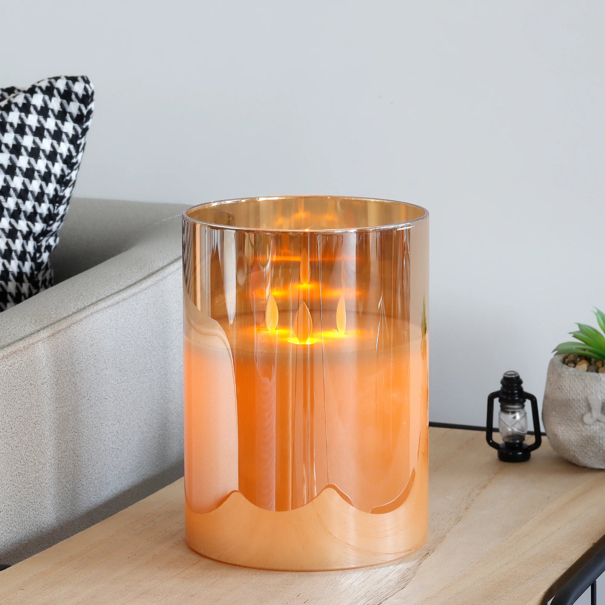 Gold glass flameless LED pillar candle on side table in modern living room, safe battery operated candle for home decor