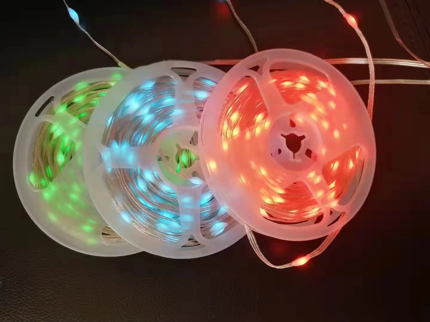 Close-up of RGBIC LED string lights coiled showing red, pink and blue color segments with IP65 waterproof casing